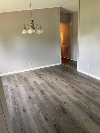 an empty room with wooden floor and chandelier