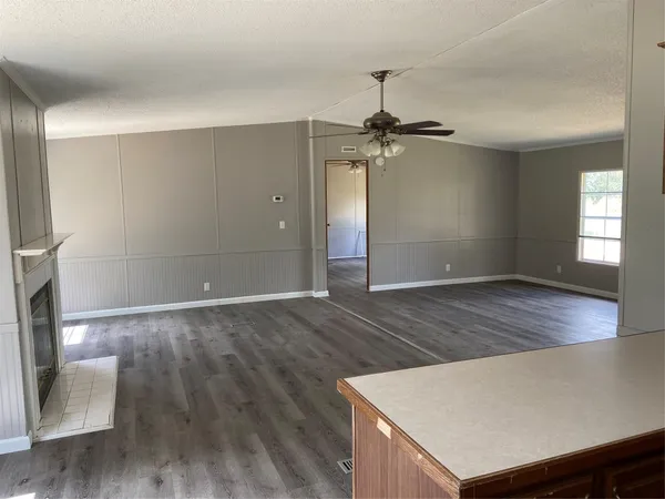 a view of an empty room with window and wooden floor