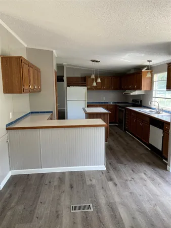 a kitchen with stainless steel appliances granite countertop a sink a stove and a wooden floors