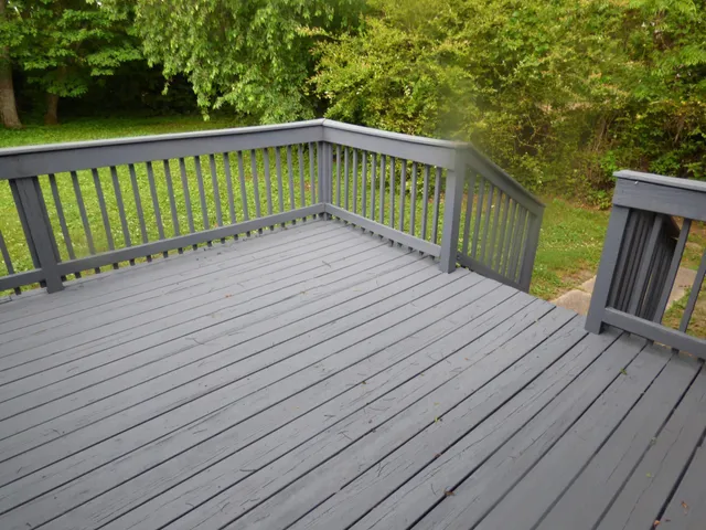 a balcony with wooden floor and trees in the back