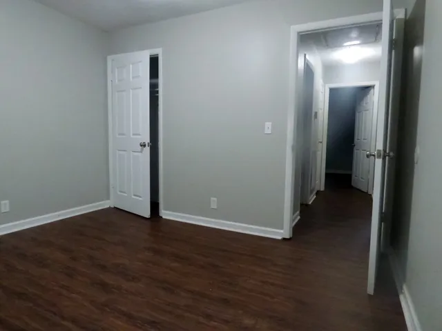 a view of an empty room with wooden floor and a bathroom