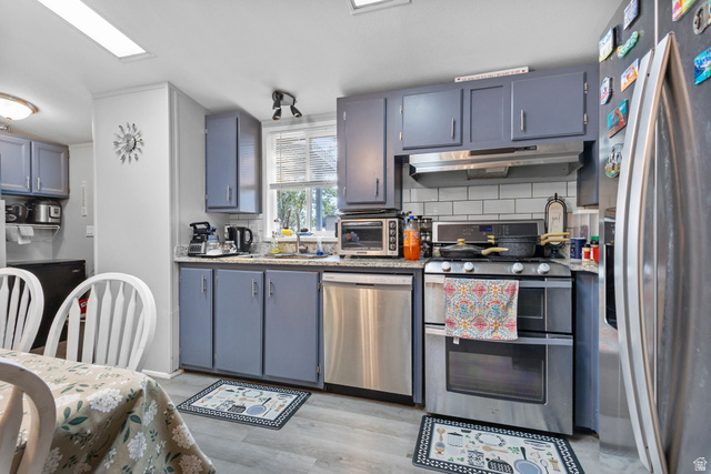 271 Mindella Way Layton, UT 84041 - Photo 11 of 27 Kitchen featuring painted gray cabinetry, stainless steel appliances, a subway tile backsplash, and wood-finish flooring