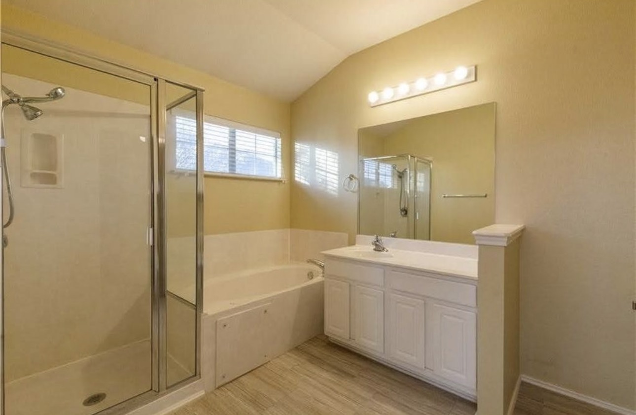 1900 Scofield Ridge Parkway, Unit 3101 Austin, TX 78727 - Photo 14 of 24 Bathroom featuring a glass-enclosed shower, built-in soaking tub, single vanity with white cabinetry, large mirror, and light wood-finish flooring
