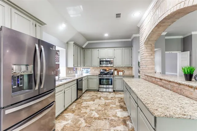 a large kitchen with kitchen island a large counter top stainless steel appliances and cabinets
