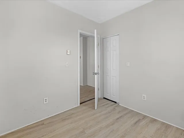 a view of an empty room with wooden floor and closet