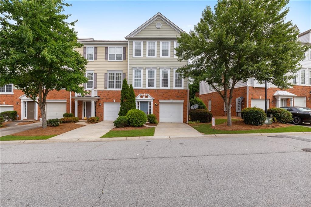 a front view of a house with a yard and large trees