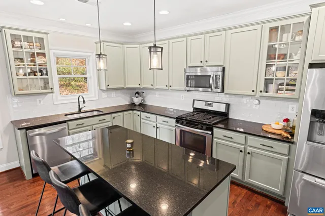 a kitchen with stainless steel appliances granite countertop a stove a sink dishwasher a microwave oven and a dining table with wooden cabinet