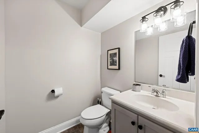 a bathroom with a toilet a sink a mirror and vanity