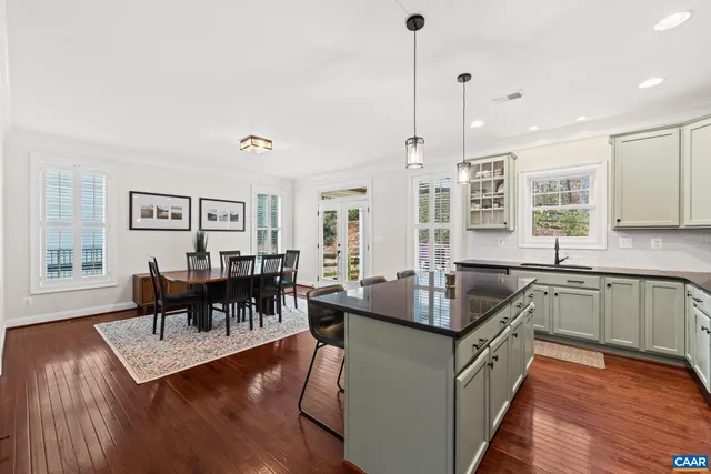 a kitchen with kitchen island granite countertop a dining table chairs and wooden floor