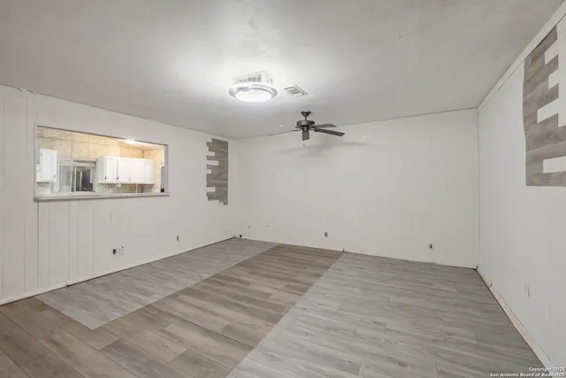 a view of empty room with wooden floor and fan