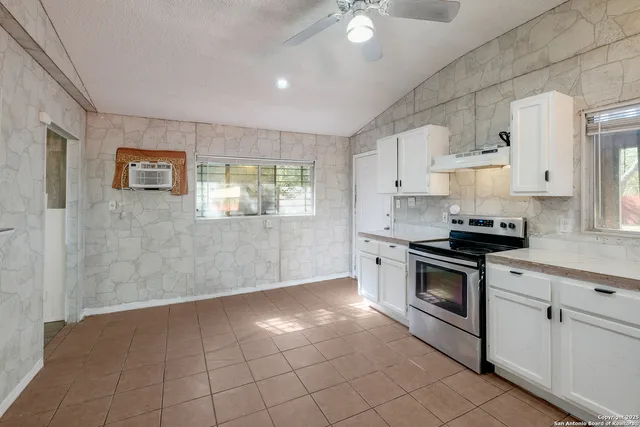 a kitchen with granite countertop a stove sink and cabinets