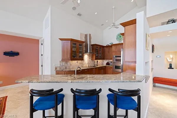 a kitchen with granite countertop a sink and chairs