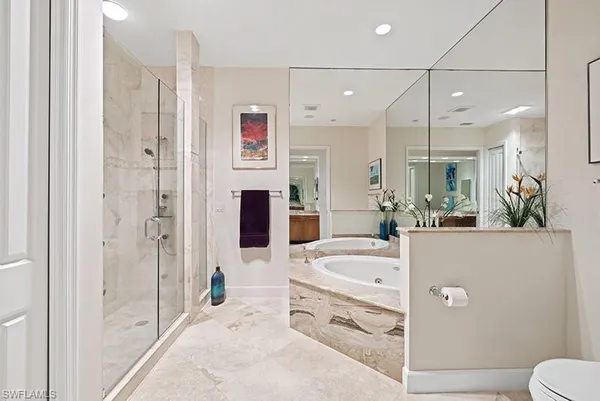 a bathroom with a tub a sink a mirror and shower
