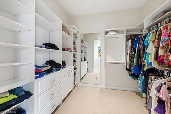 a view of walk in closet with clothes and shoes