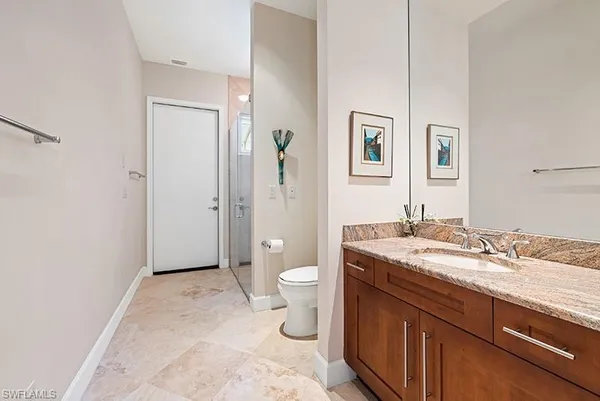 a spacious bathroom with a granite countertop toilet sink and mirror