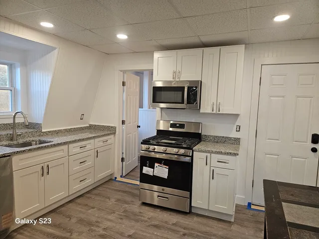 a kitchen with granite countertop white cabinets and stainless steel appliances