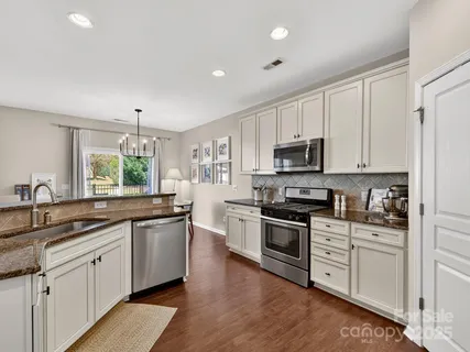a kitchen with granite countertop white cabinets and stainless steel appliances