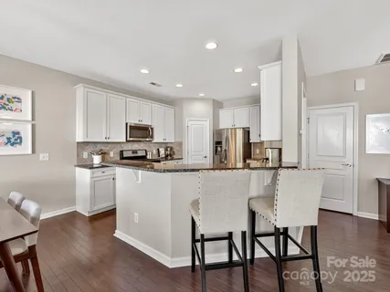 a kitchen with stainless steel appliances granite countertop a table chairs refrigerator and sink