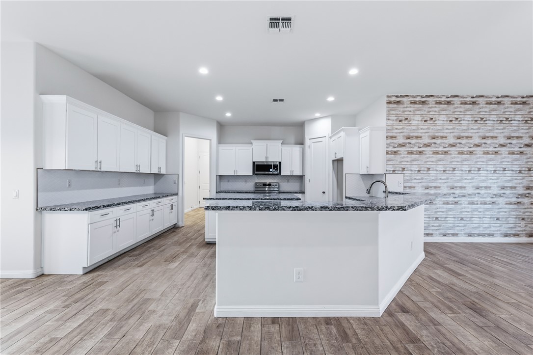 2385 Corwin Road Bullhead City, AZ 86442 - Photo 18 of 78 a large kitchen with stainless steel appliances kitchen island granite countertop a stove a sink a refrigerator and white cabinets with wooden floor