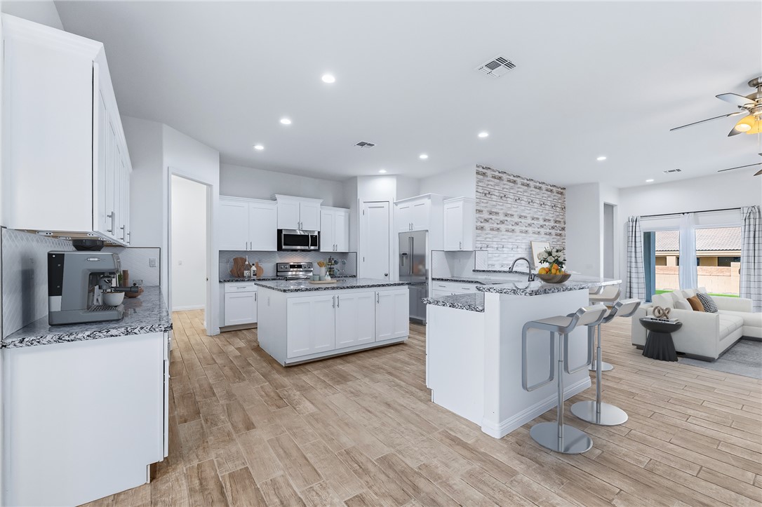 2385 Corwin Road Bullhead City, AZ 86442 - Photo 21 of 78 a kitchen with stainless steel appliances kitchen island granite countertop a stove top oven a sink a refrigerator and white cabinets with wooden floor