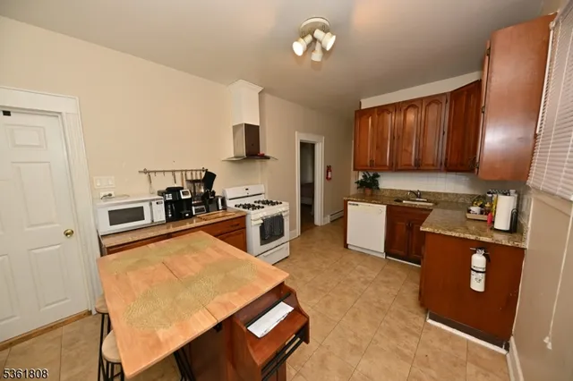 a kitchen with stainless steel appliances granite countertop a stove top oven a sink a dining table and chairs with wooden floor