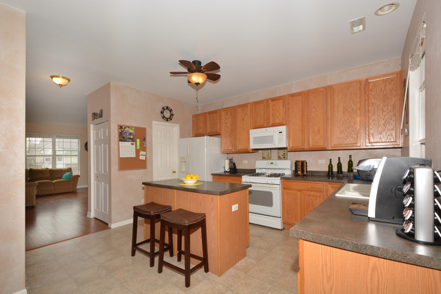 285 South Oak Creek Lane, Unit 285 Romeoville, IL 60446 - Photo 2 of 24 a kitchen with kitchen island granite countertop a sink cabinets and stainless steel appliances