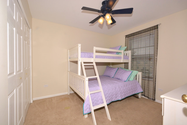 285 South Oak Creek Lane, Unit 285 Romeoville, IL 60446 - Photo 16 of 24 a bedroom with a bed and a chandelier