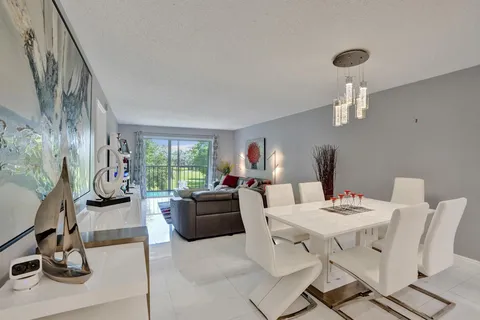 a living room with furniture a chandelier and kitchen view