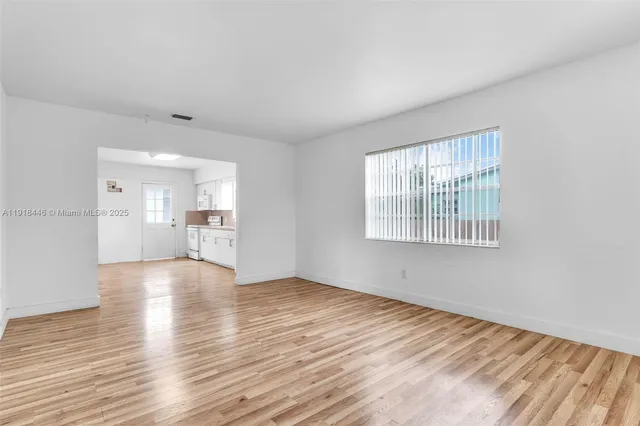 a view of empty room with wooden floor and windows