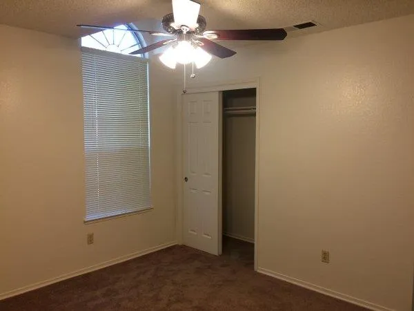 a view of an empty room and chandelier fan