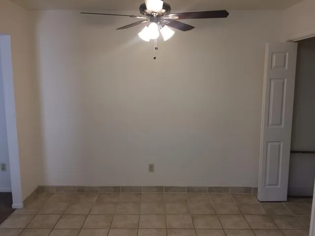 an empty room with windows and chandelier fan