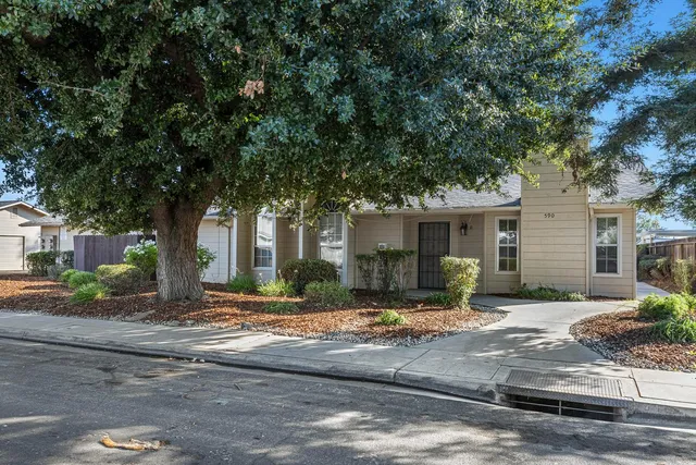 a front view of a house with yard and trees around