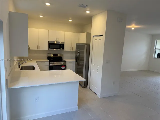 a large kitchen with stainless steel appliances a refrigerator and a stove