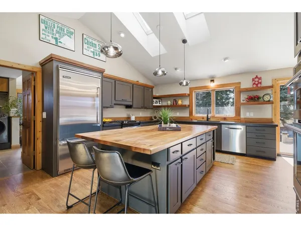 a kitchen with stainless steel appliances granite countertop a table chairs sink and cabinets