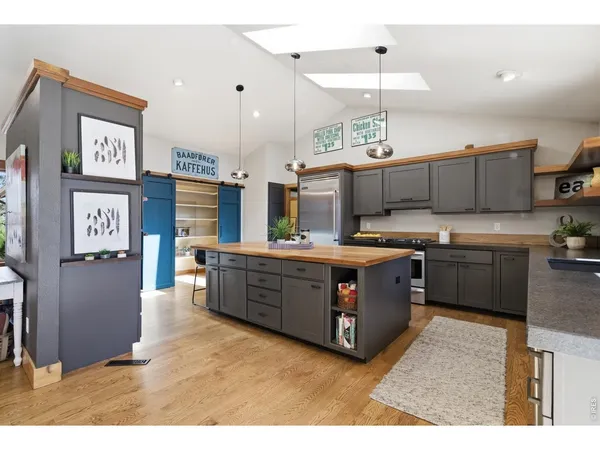 a large kitchen with stainless steel appliances kitchen island granite countertop a stove a sink a refrigerator and a microwave