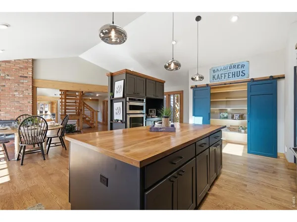 a dining hall with stainless steel appliances granite countertop a sink a kitchen island a stove and a wooden floors