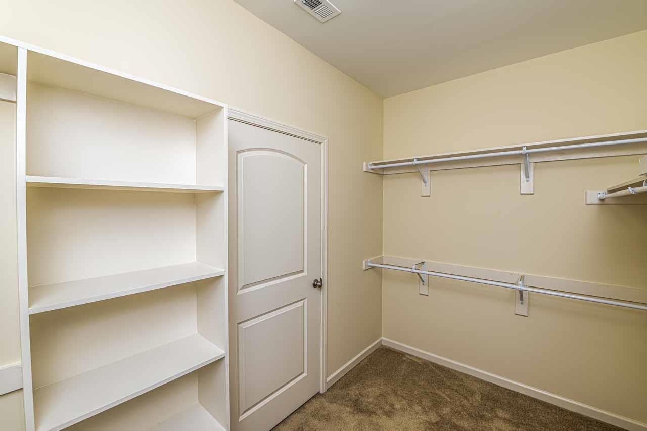 185 Belmont Road Mason, TN 38049 - Photo 16 of 38 Closet featuring built-in shelving, multiple hanging rods, and neutral-toned carpeting