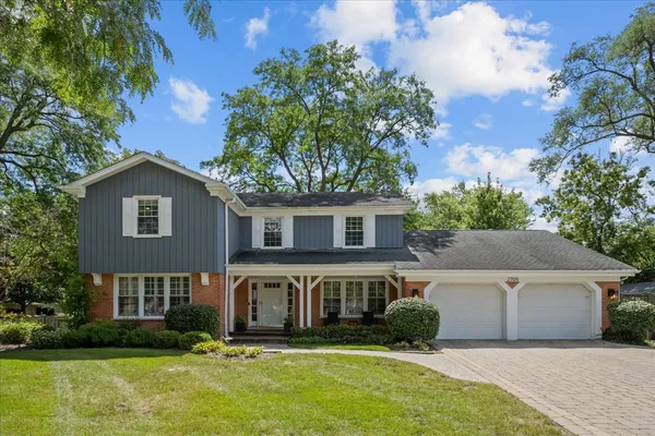 a view of a house with a small yard plants and a large tree