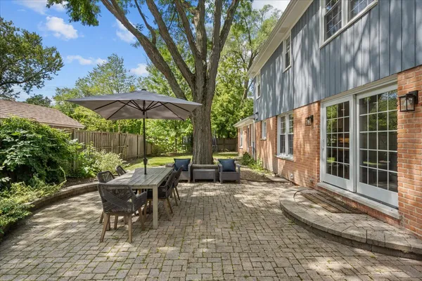 a view of a patio with a table and chairs under an umbrella with barbeque grill and wooden fence