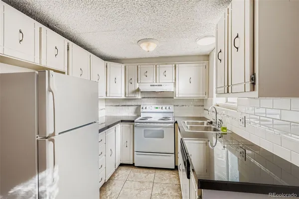 a kitchen with granite countertop a sink cabinets and stove