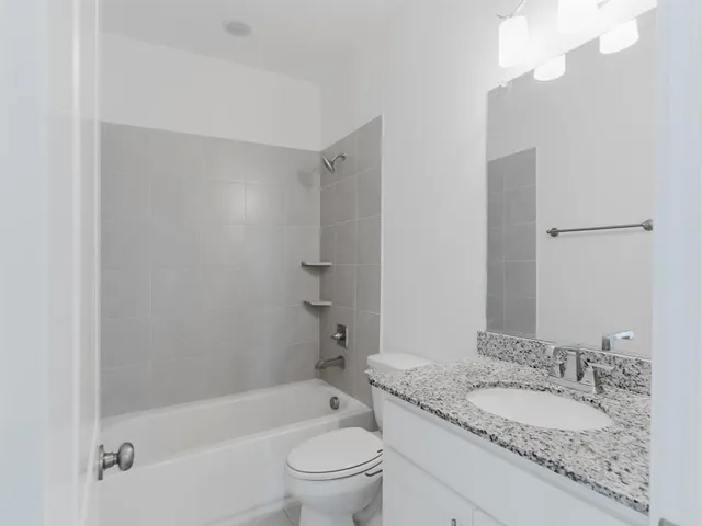 a bathroom with a granite countertop toilet a sink and a bathtub