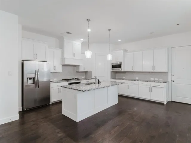 a kitchen with stainless steel appliances white cabinets a sink a stove a refrigerator and white cabinets