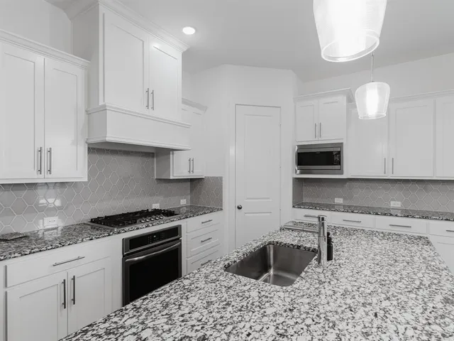 a kitchen with granite countertop a sink a stove and cabinets