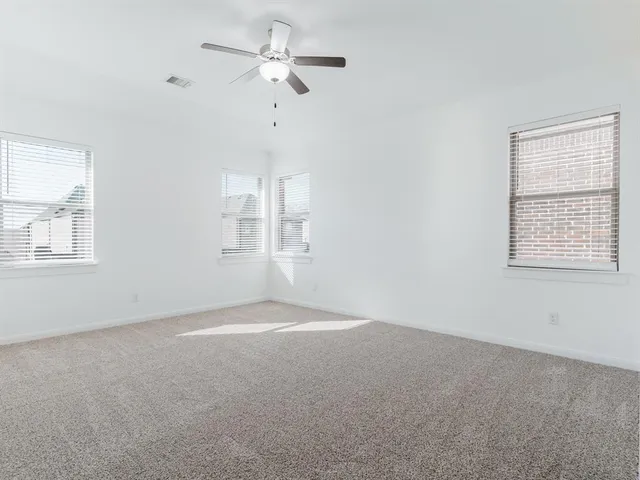 en empty room with windows and ceiling fan