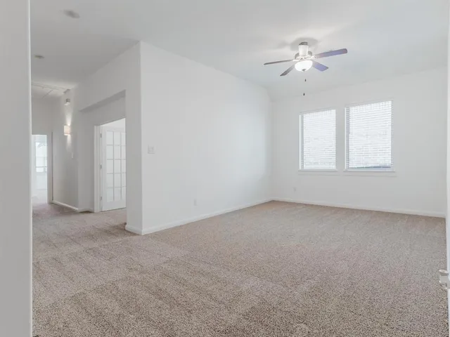 a view of an empty room with a chandelier fan