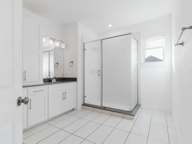 a spacious bathroom with a mirror a shower and a sink