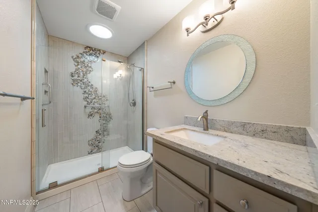a bathroom with a granite countertop sink a toilet and shower