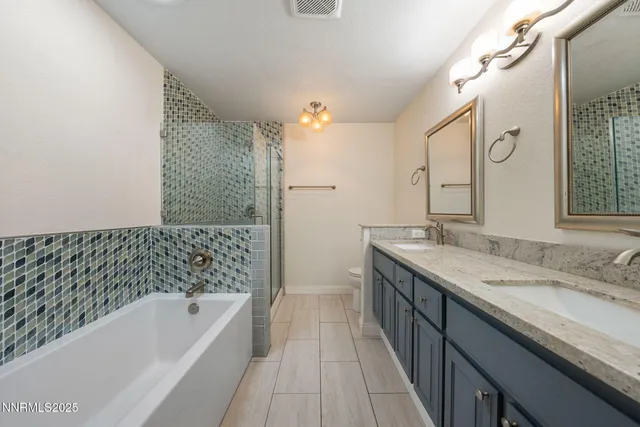 a bathroom with a granite countertop sink a toilet a mirror a bathtub and shower