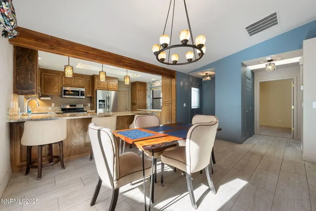 a dining room with wooden floor a chandelier a glass table and chairs