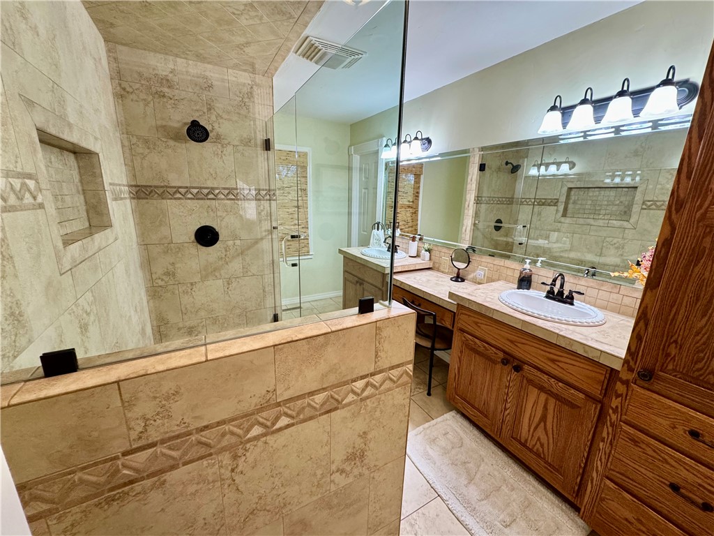 15196 Cincinnati Creek Road Summers, AR 72769 - Photo 20 of 42 Spacious bathroom featuring a tiled walk-in shower with a recessed niche, dual shower heads, and a clear glass enclosure